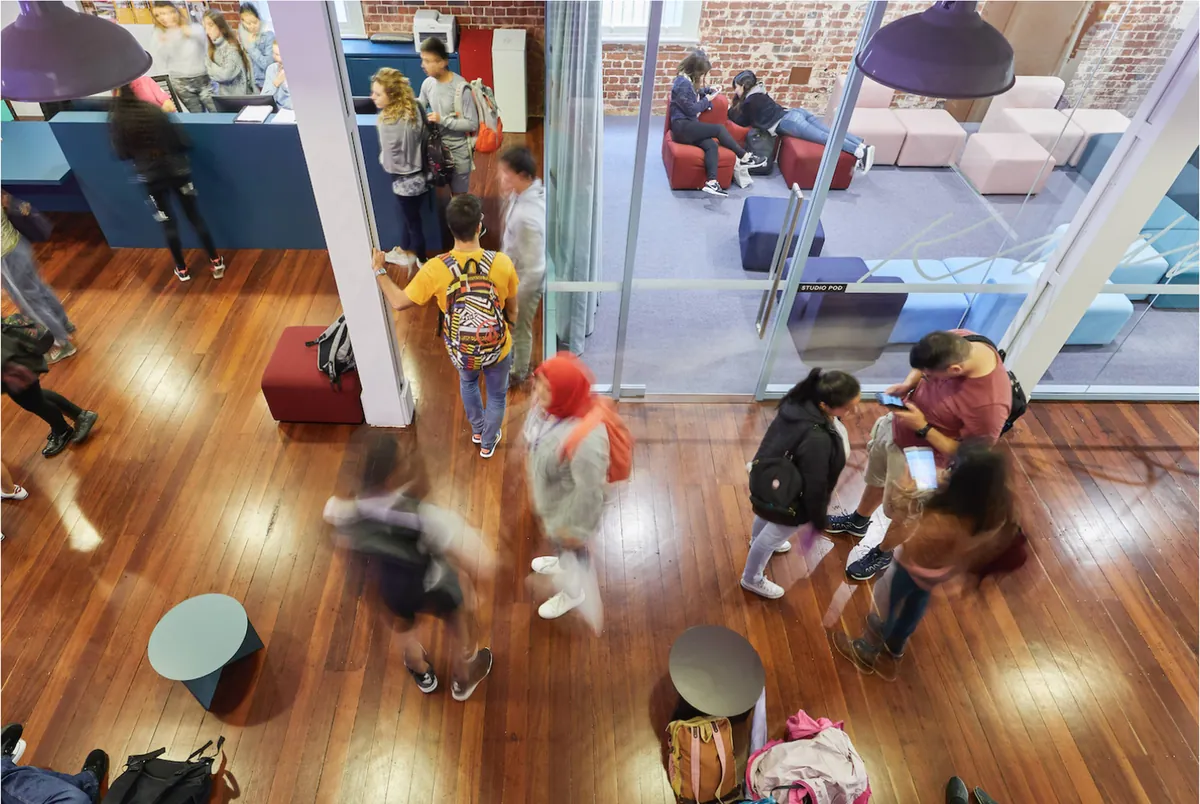 Studenten lopen door een lichte, open EF-school met glazen studieruimtes.
