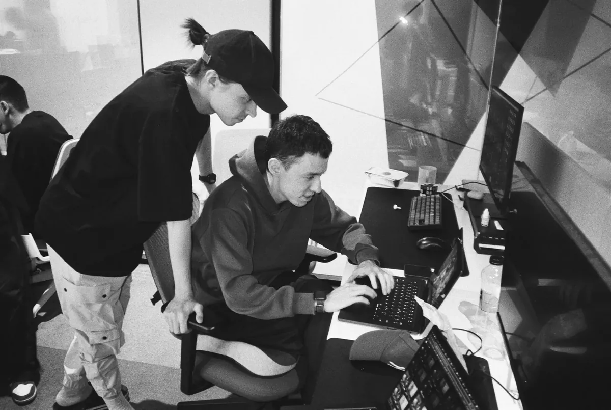 Twee teamleden van Higgsfield die samen aan een computer werken, in zwart-wit gefotografeerd.